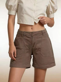 Person wearing brown shorts and a white blouse on a beige background