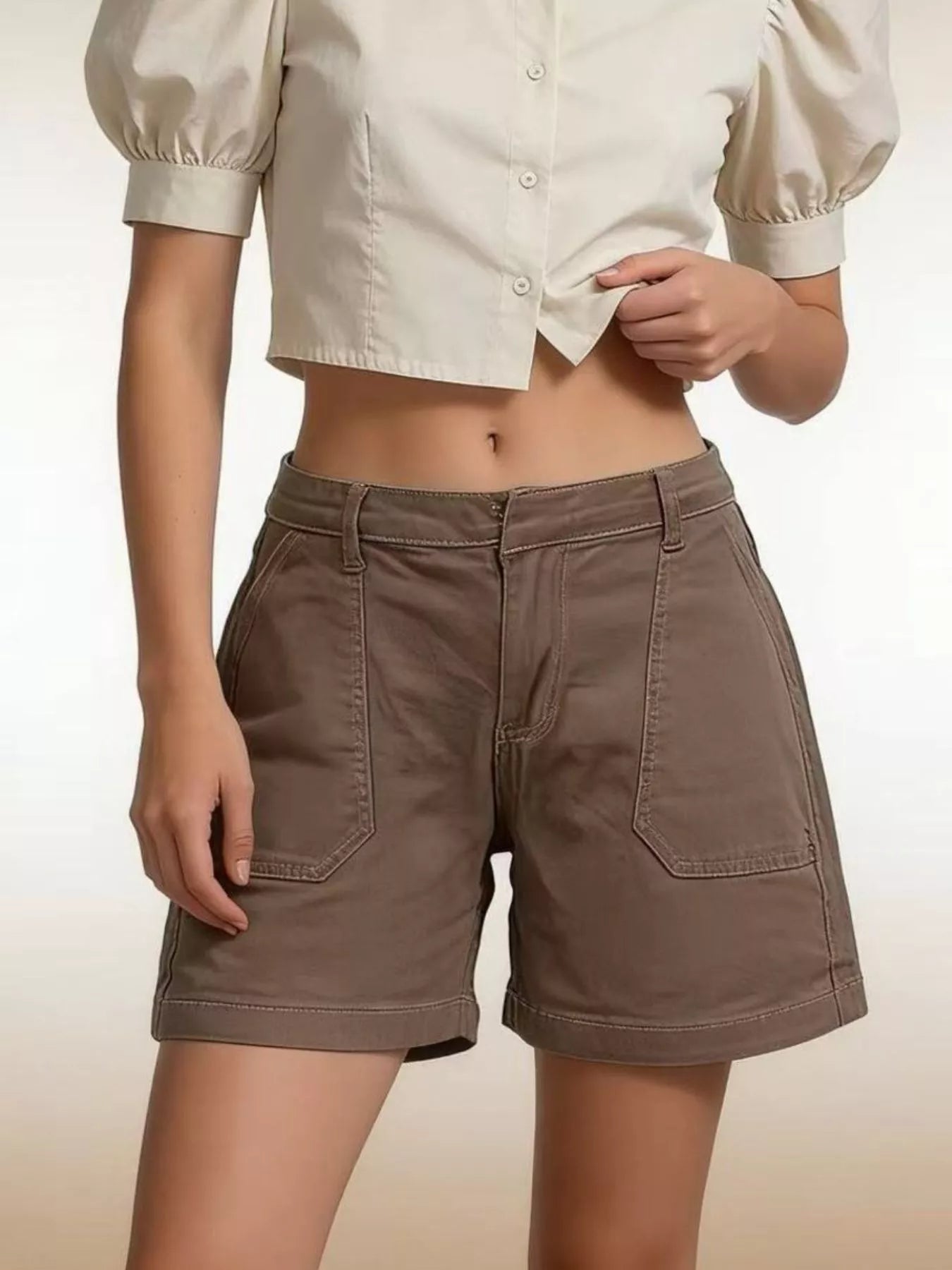 Person wearing brown shorts and a white blouse on a beige background