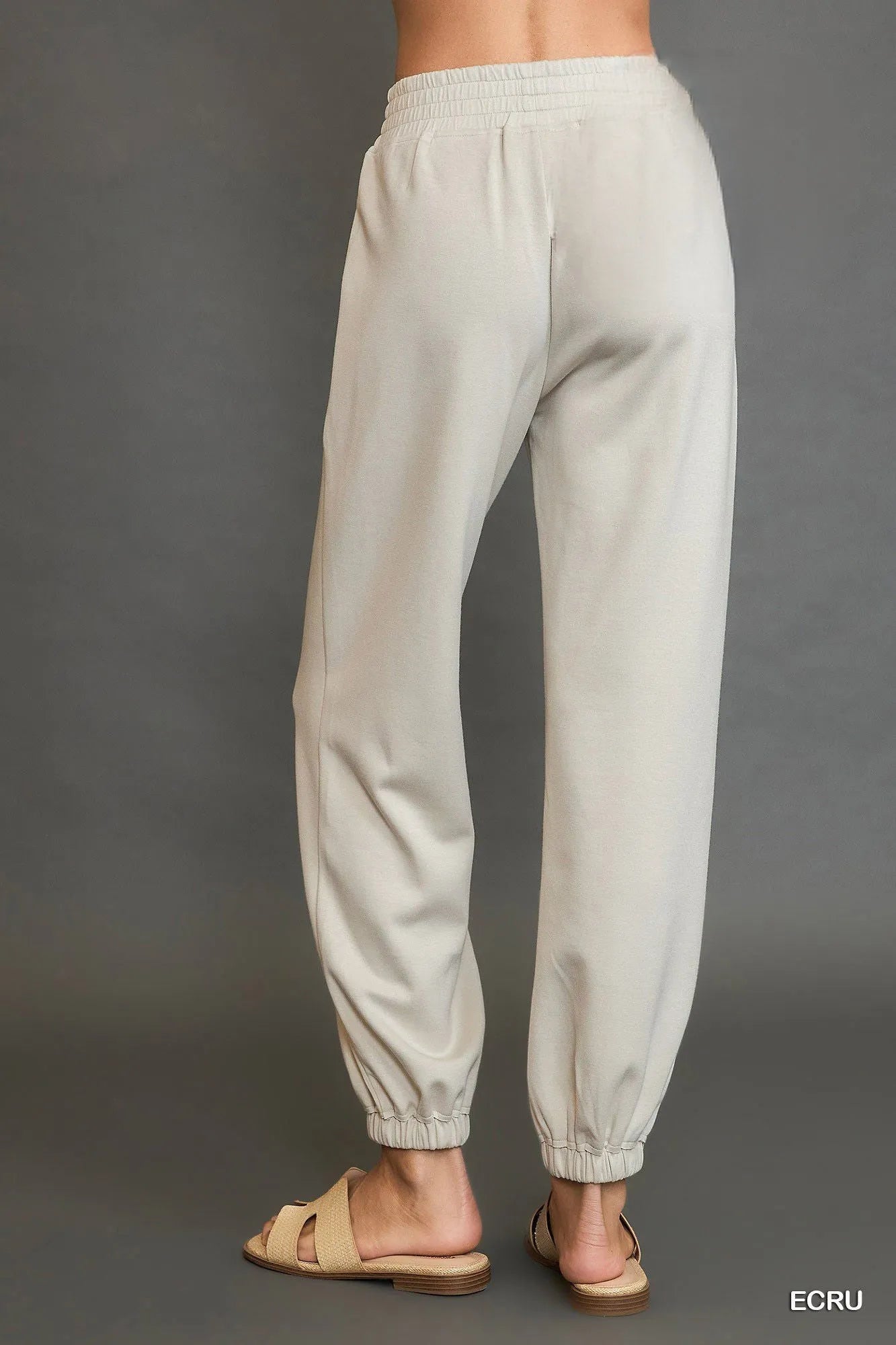 Light gray sweatpants worn by a person on a gray background