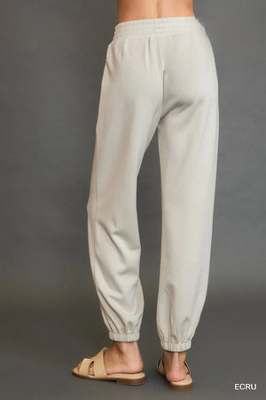 Light gray sweatpants worn by a person on a gray background