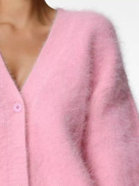 Close-up of a pink cardigan with a button detail on a white background