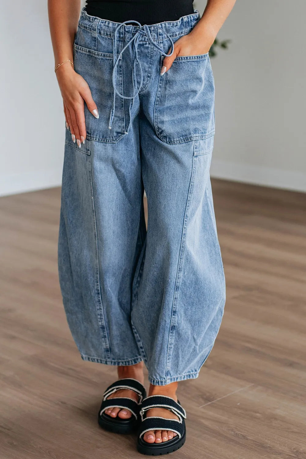 Person wearing wide-leg blue jeans on a wooden floor.