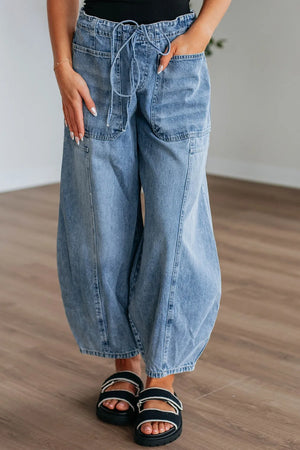 Person wearing wide-leg blue jeans on a wooden floor.