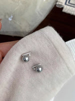 Silver earrings with pearls on a textured surface