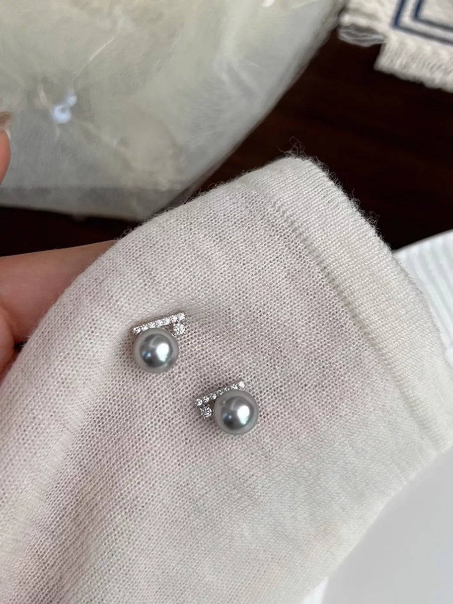Silver earrings with pearls on a textured surface