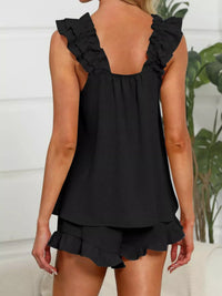 Black ruffled top and shorts set worn by a person, with a blurred background.
