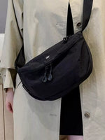 Person wearing a black shoulder bag with a visible brand logo.