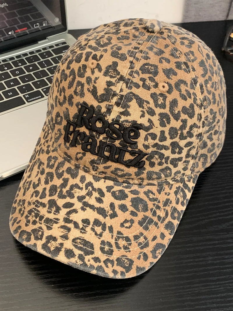 Leopard print cap with 'Nose Printz' logo on a black surface next to a laptop.