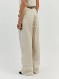 Beige linen pants worn by a person on a white background