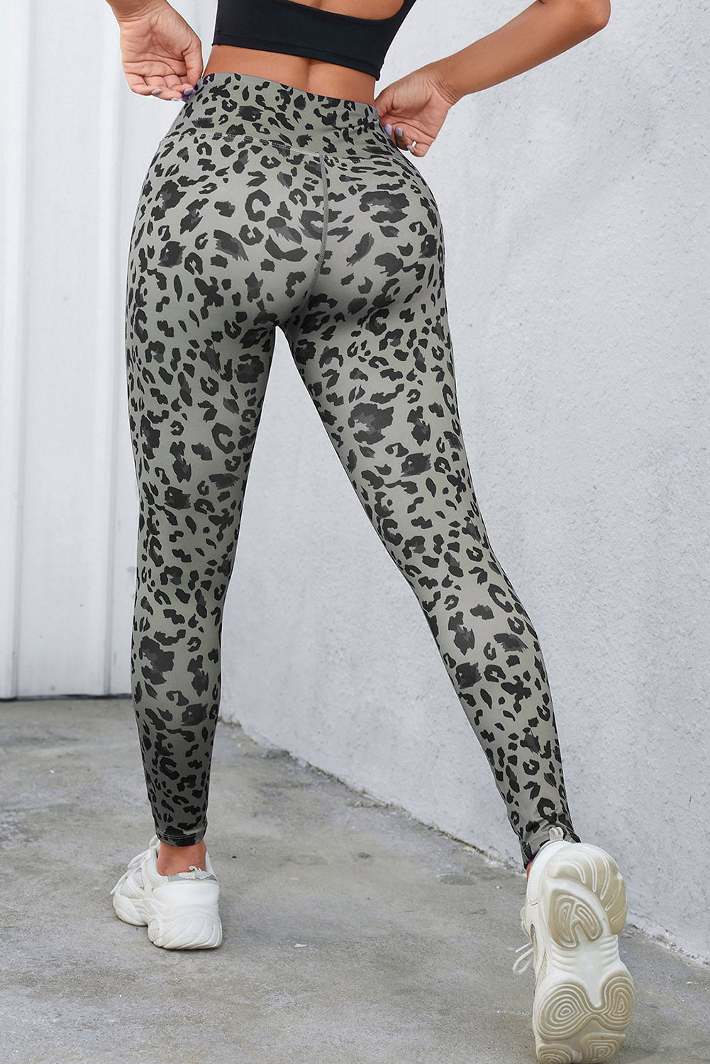 Person wearing gray leopard print leggings against a white wall.