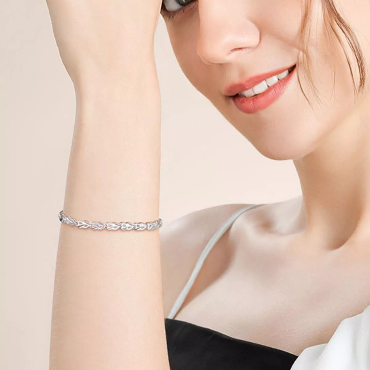 Woman wearing a silver bracelet on a beige background