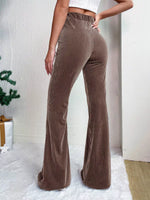 Brown corduroy flared pants worn by a person on a white background