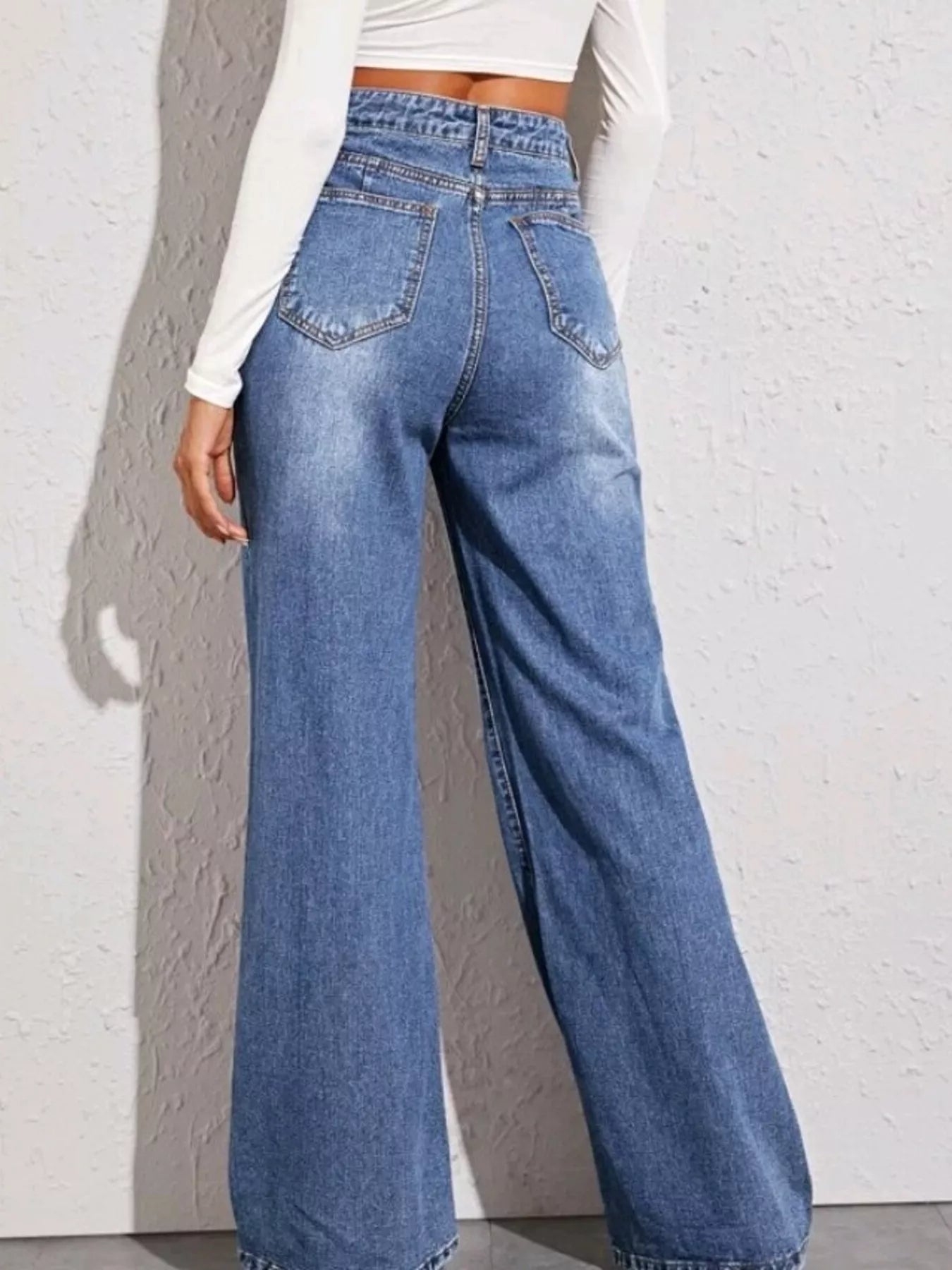 Person wearing high-waisted blue jeans against a light gray background