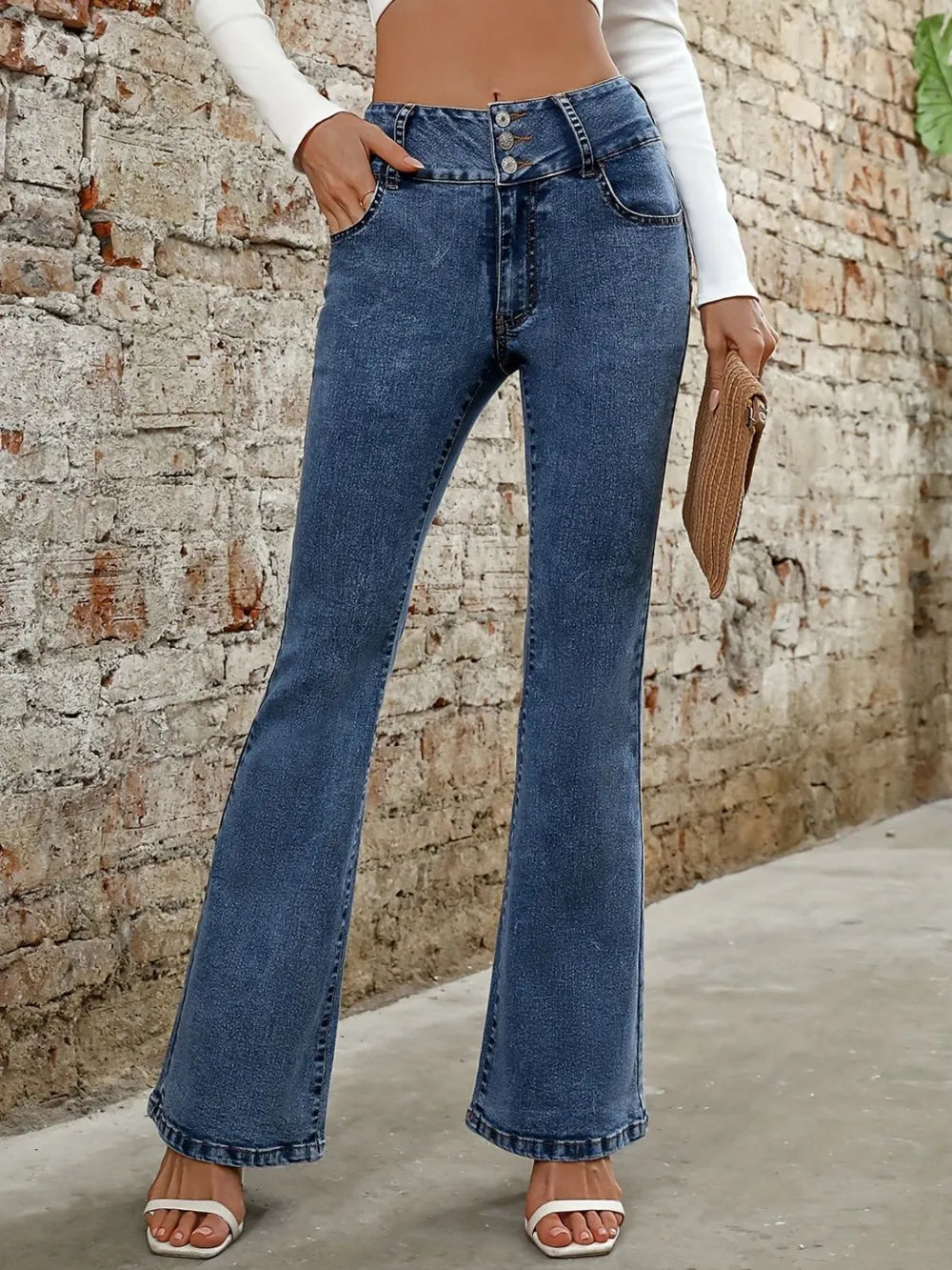 Person wearing blue flared jeans against a brick wall.