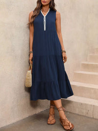 Woman wearing a navy blue dress with white trim, standing against a neutral wall.