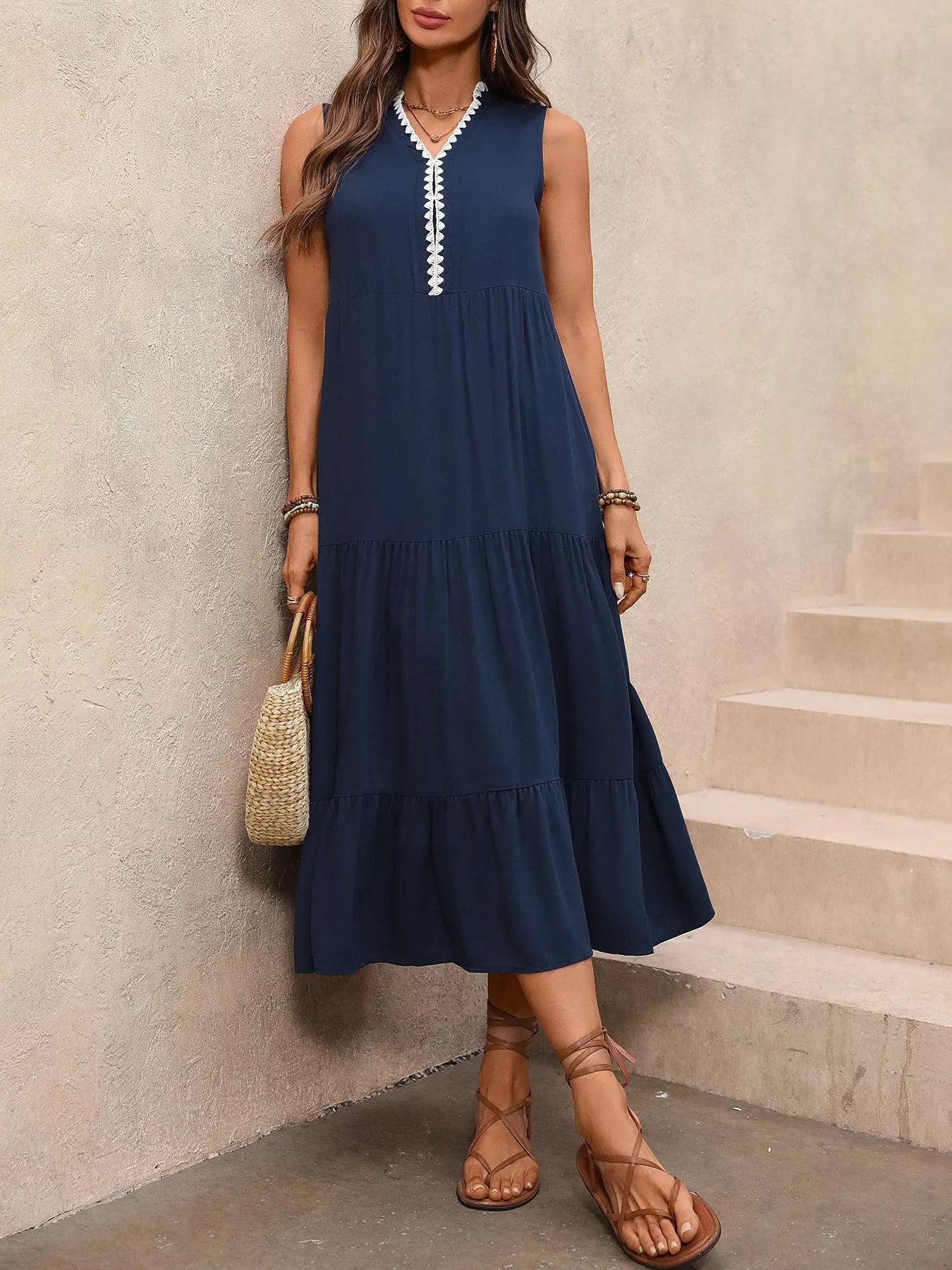 Woman wearing a navy blue dress with white trim, standing against a neutral wall.