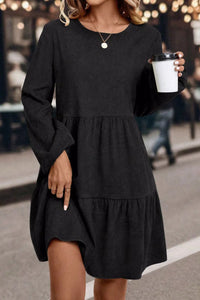 Woman wearing a black dress holding a cup outdoors