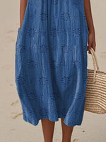 Woman wearing a blue dress with a geometric pattern on a beach.