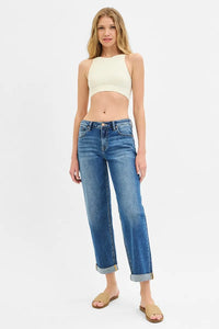 Woman wearing a yellow crop top and blue jeans on a white background
