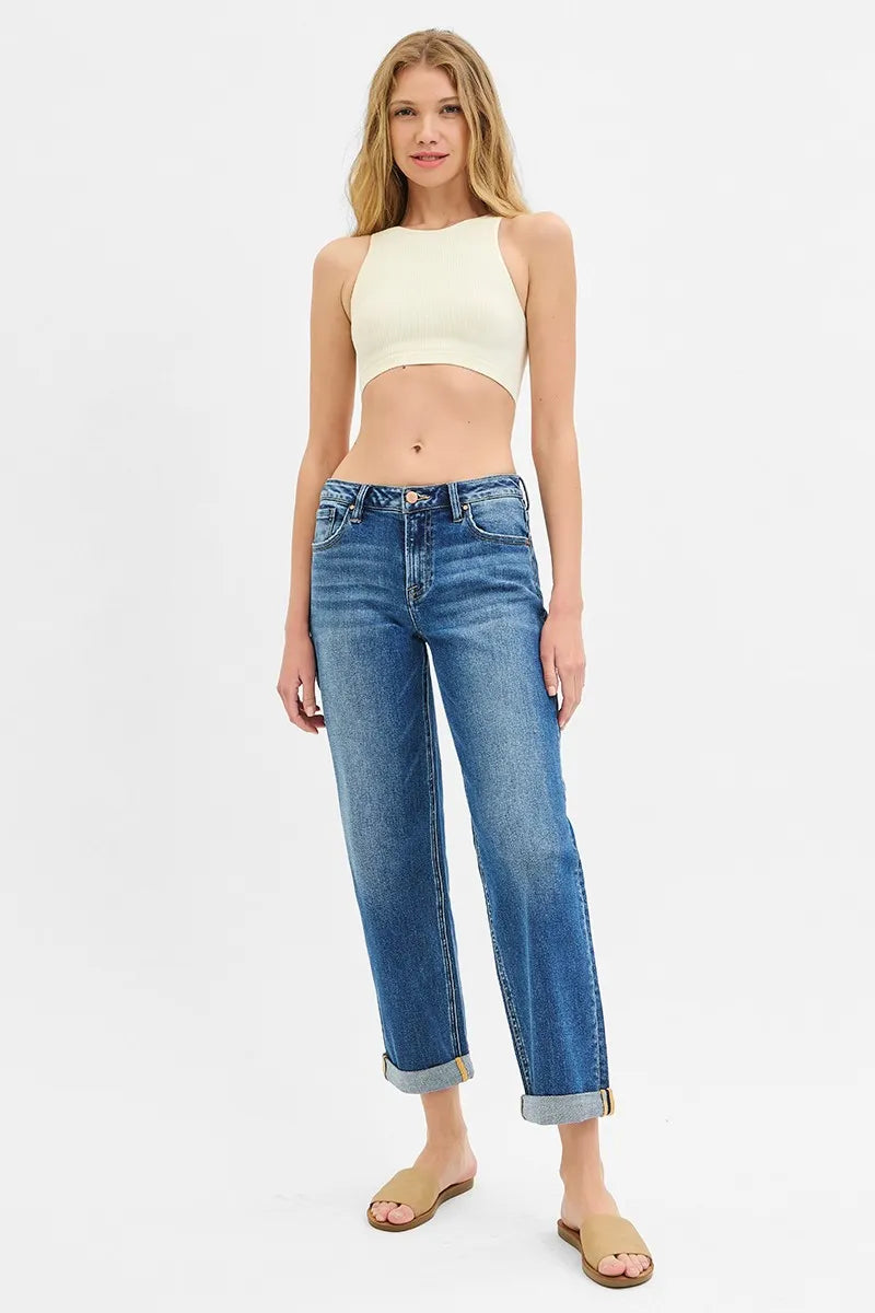 Woman wearing a yellow crop top and blue jeans on a white background