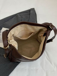 Brown leather bag with beige interior on a white background