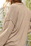 Close-up of a beige textured sweater worn by a person with a blurred background