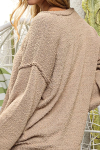 Close-up of a beige textured sweater worn by a person with a blurred background