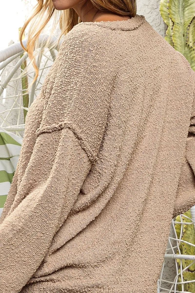 Close-up of a beige textured sweater worn by a person with a blurred background
