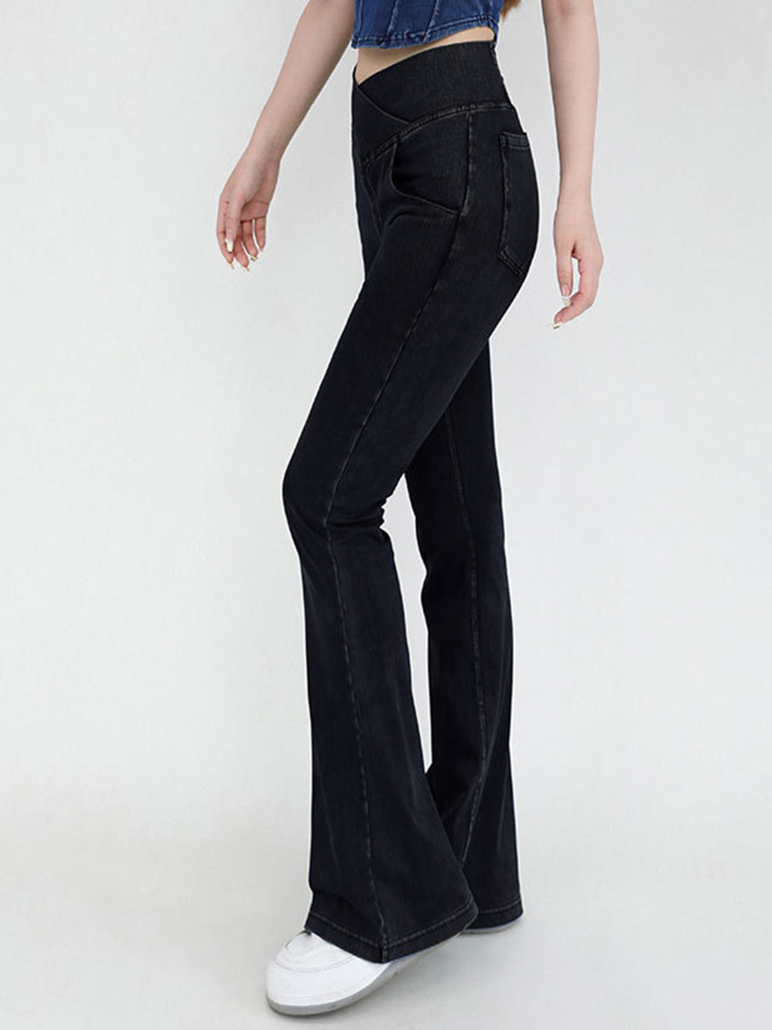 Black flared jeans worn by a person on a white background