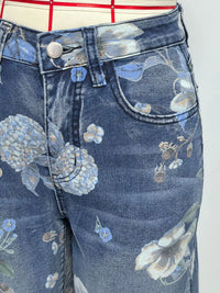 Close-up of blue jeans with floral embroidery on a white background