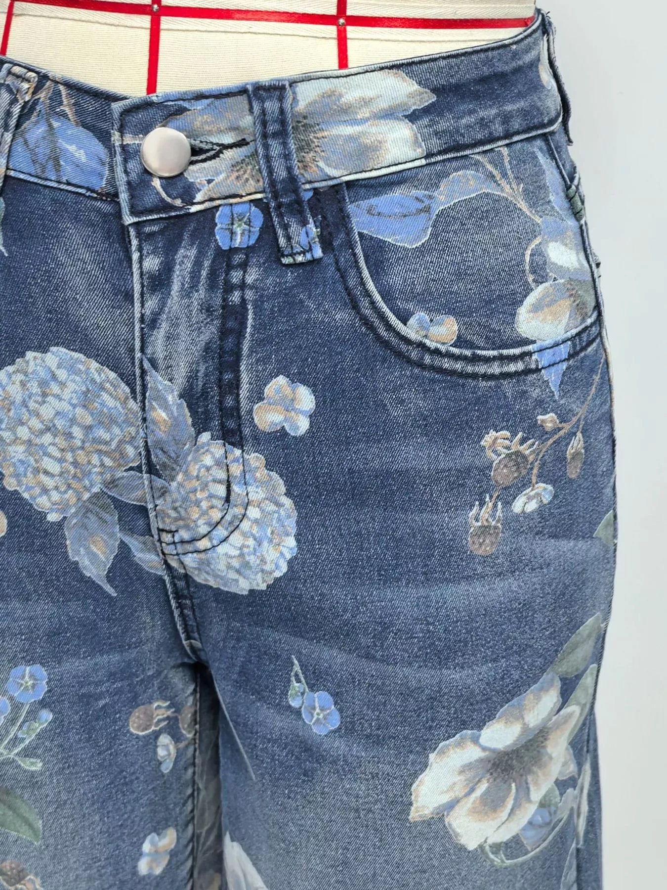 Close-up of blue jeans with floral embroidery on a white background