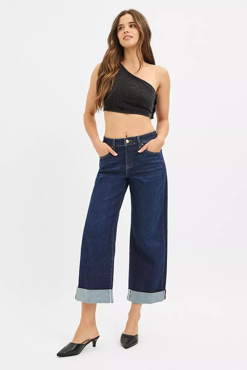 Woman wearing a black one-shoulder top and blue jeans on a white background