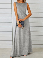 Woman wearing a gray sleeveless dress against a wooden wall.