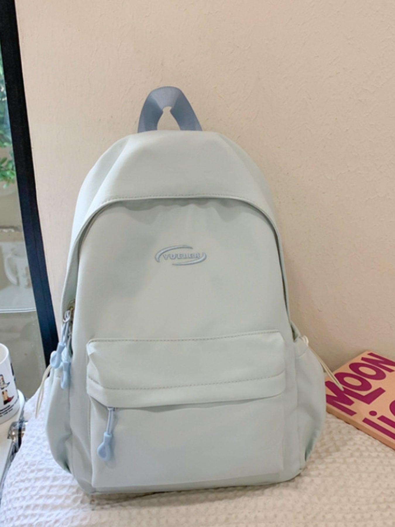 Light blue backpack on a bed with a neutral background