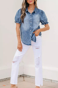 Woman wearing a denim shirt and white pants against a light background