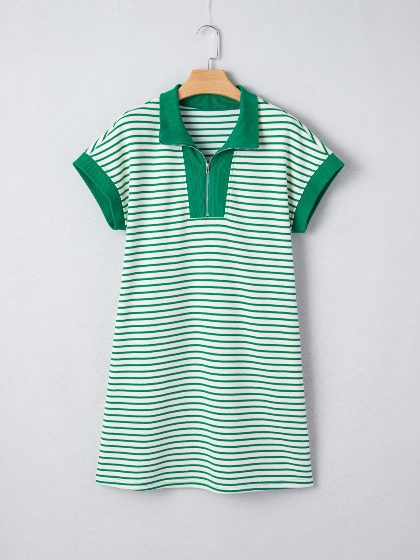 Green and white striped dress on a hanger against a light gray background