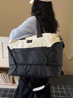 Person carrying a black and beige bag with a visible brand logo.