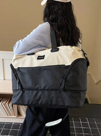 Person carrying a black and beige bag with a visible brand logo.