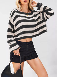 Person wearing a black and white striped sweater and black shorts on a plain background