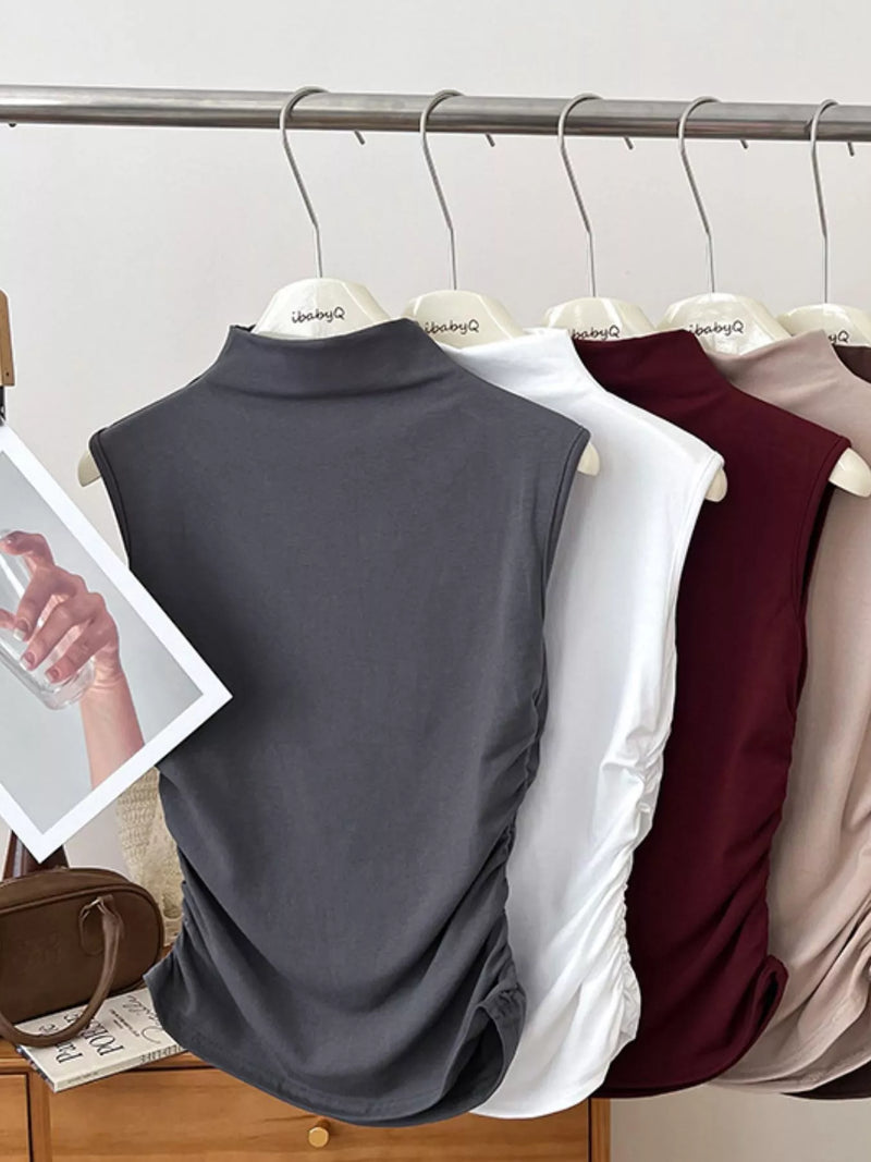 Collection of sleeveless tops in various colors hanging on a rack.