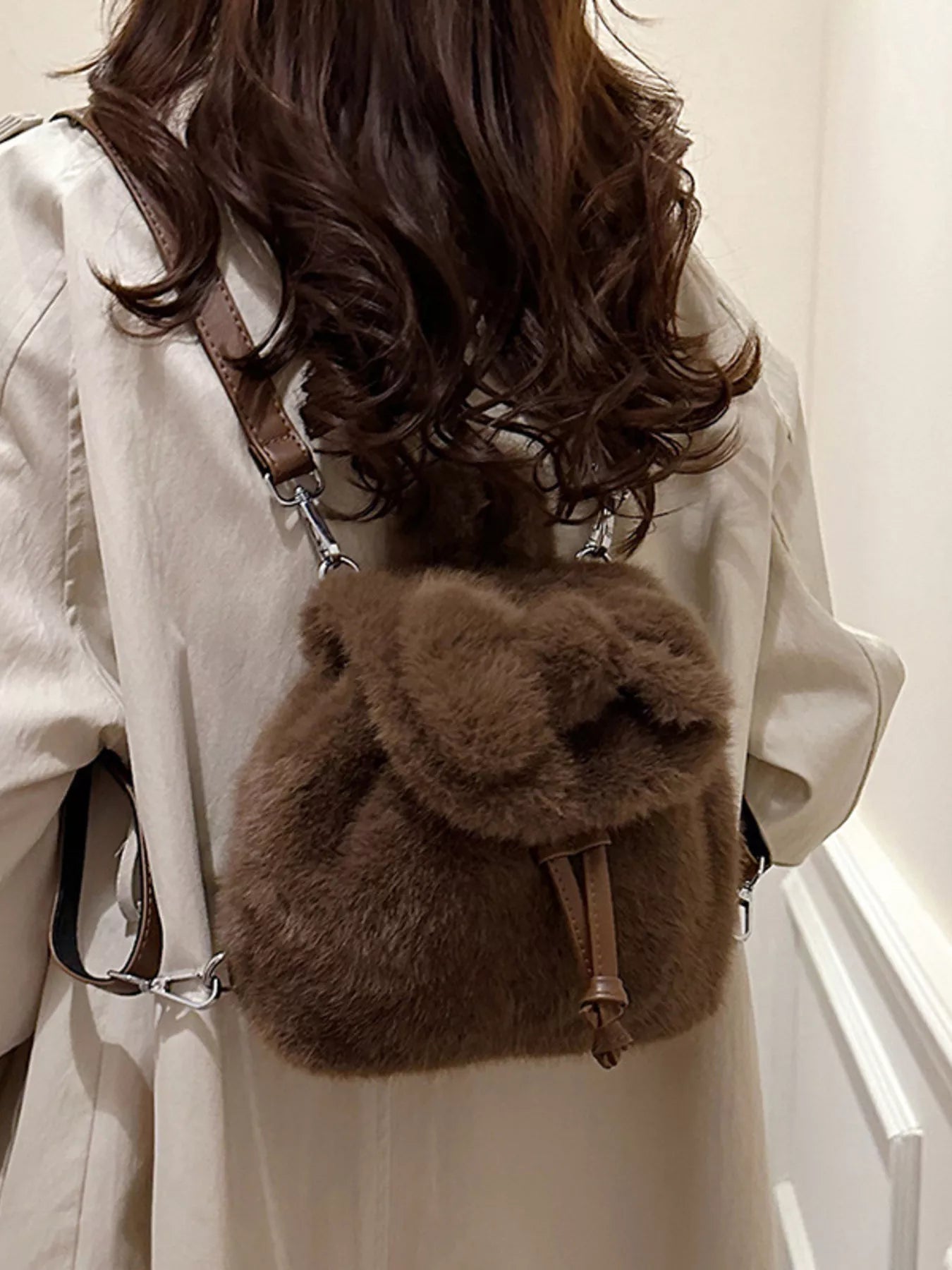 Person wearing a fluffy brown backpack with a neutral background