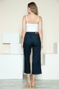 Woman wearing a white top and dark blue jeans standing on a staircase.