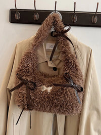 Brown fur vest with a belt over a beige coat on a rack.