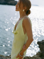 Woman in a yellow dress standing by the water