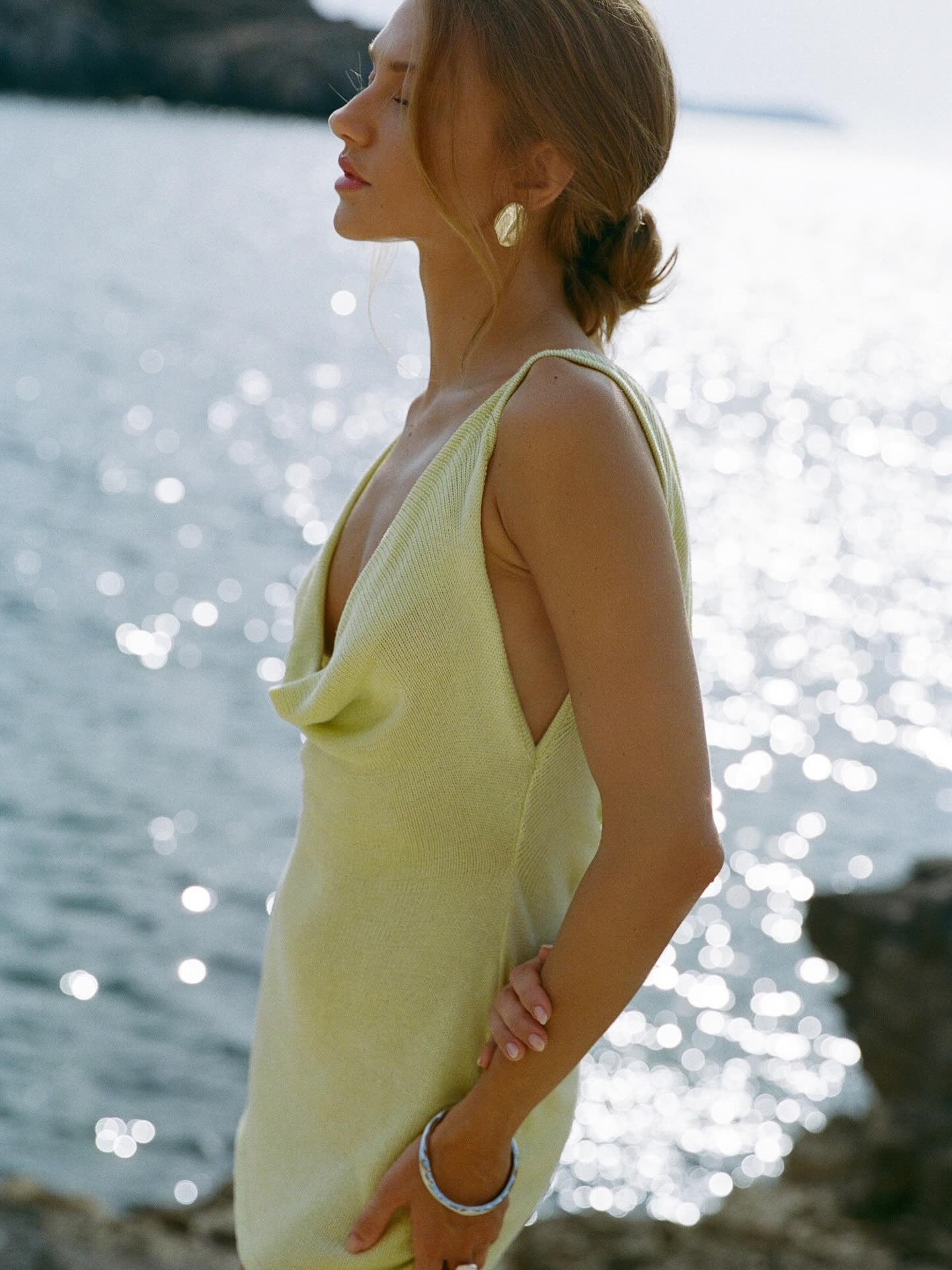 Woman in a yellow dress standing by the water