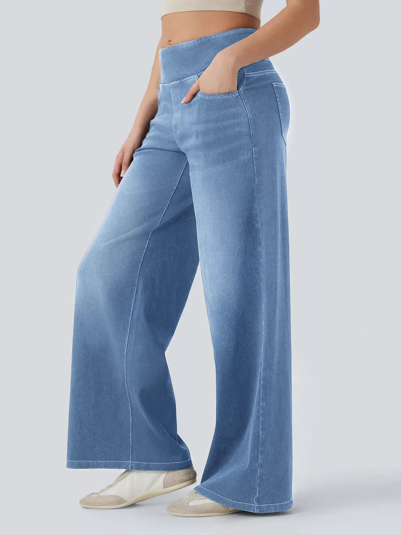 Person wearing light blue wide-leg jeans on a plain background