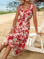 Woman in a red and white floral dress sitting on a beach chair at the beach.