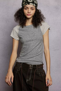 Woman wearing a gray t-shirt and dark pants against a gray background