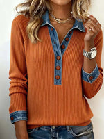Person wearing an orange sweater with denim collar and cuffs on a plain background
