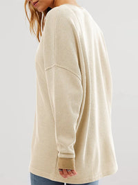 Beige long-sleeve shirt worn by a person on a plain background